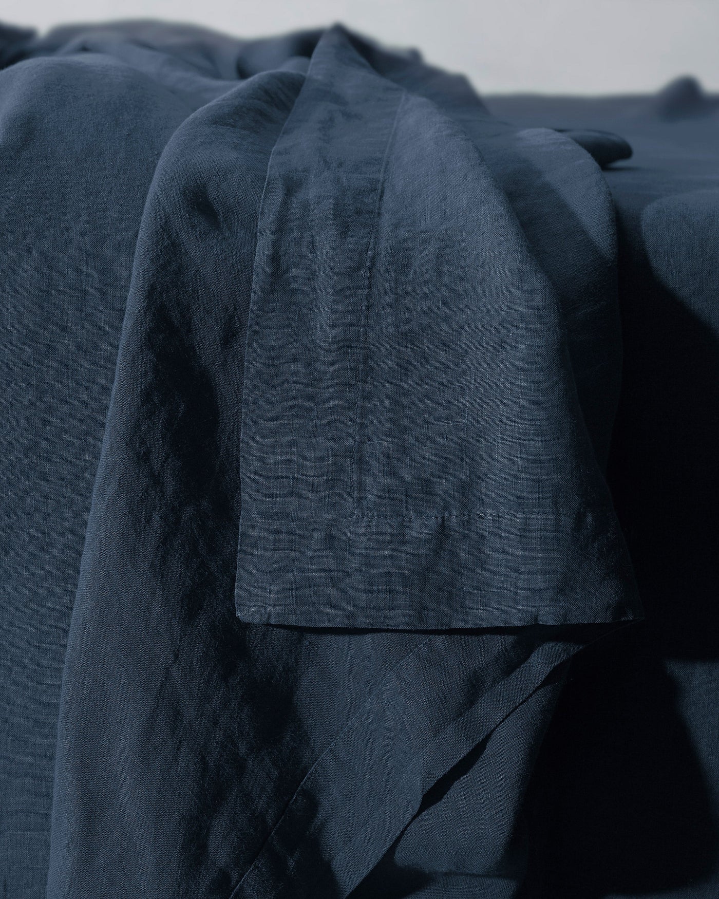 Close-up of Society Limonta Rem flat sheet hem detail in midnight blue linen.