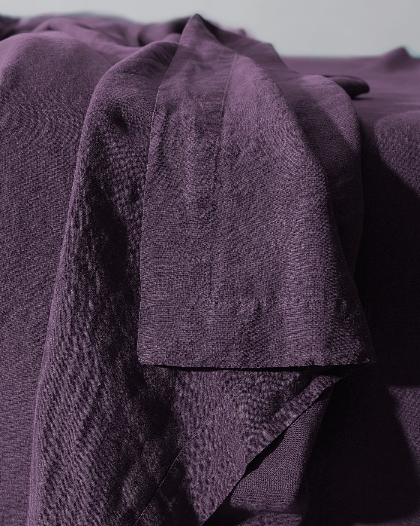 Close-up of Society Limonta Rem flat sheet hem detail in deep plum linen.