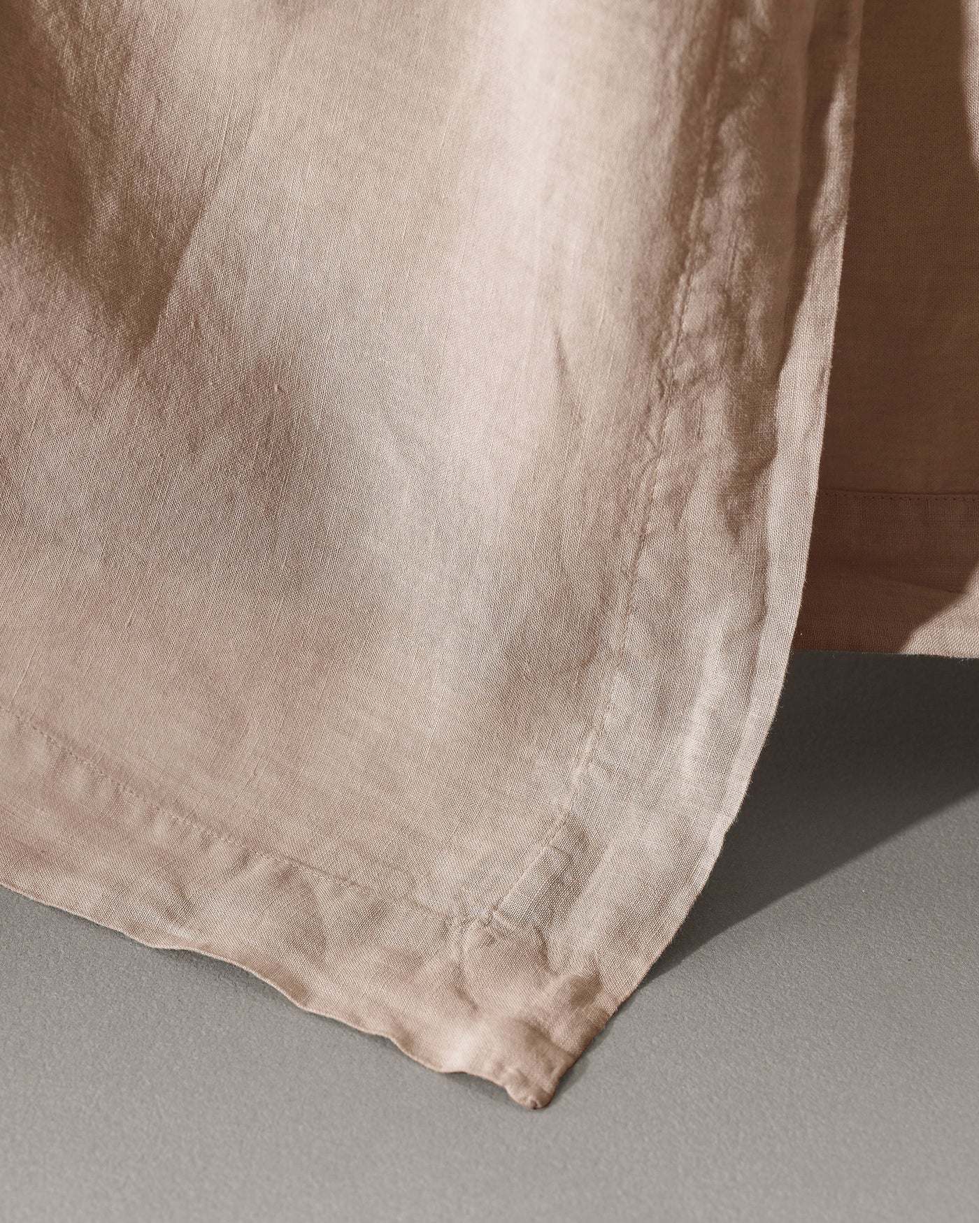 Close-up of Society Limonta Rem flat sheet hem in sandy linen with natural texture detail.