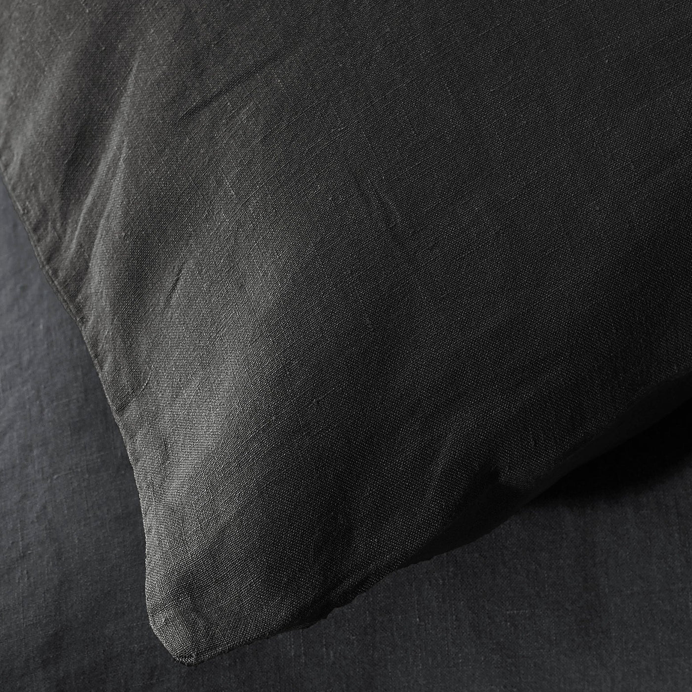 Close-up of Society Limonta Rem pillowcase in charcoal linen, showing relaxed texture and corner detail.