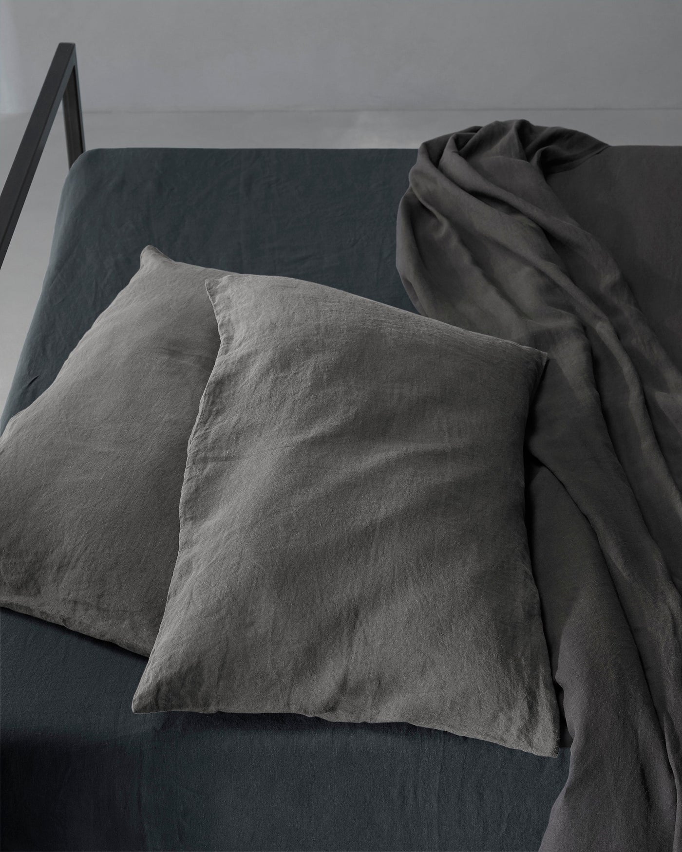 Overhead angle showing charcoal linen pillowcases against matching fitted sheet with draped duvet.