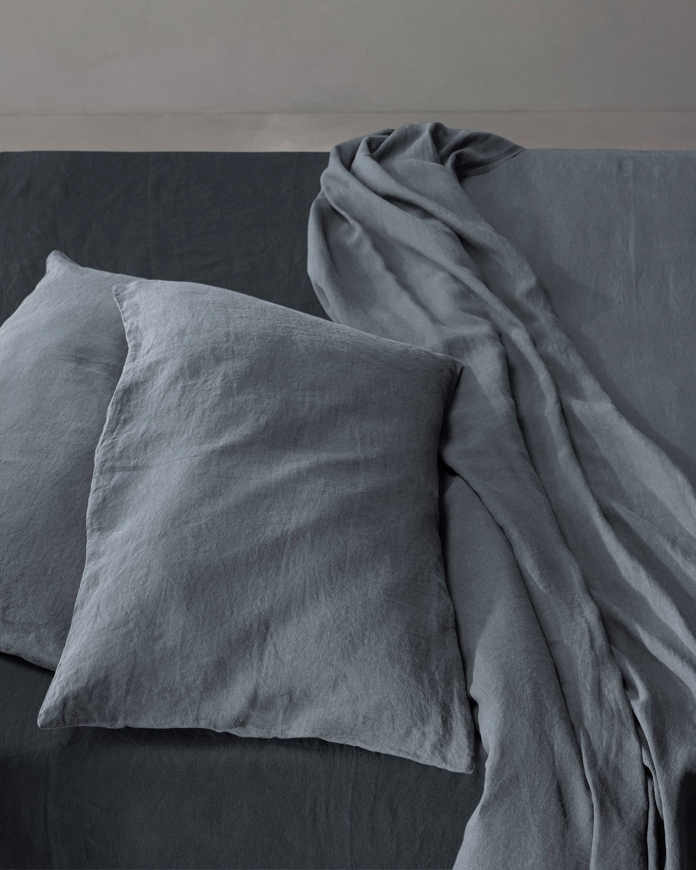 Society Limonta Rem pillowcase set in slate blue washed linen on a made bed.