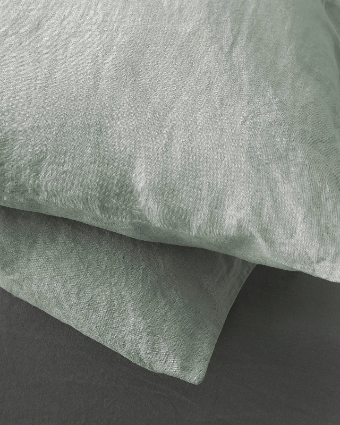 Close-up of sage linen pillowcase with natural washed texture and relaxed drape.