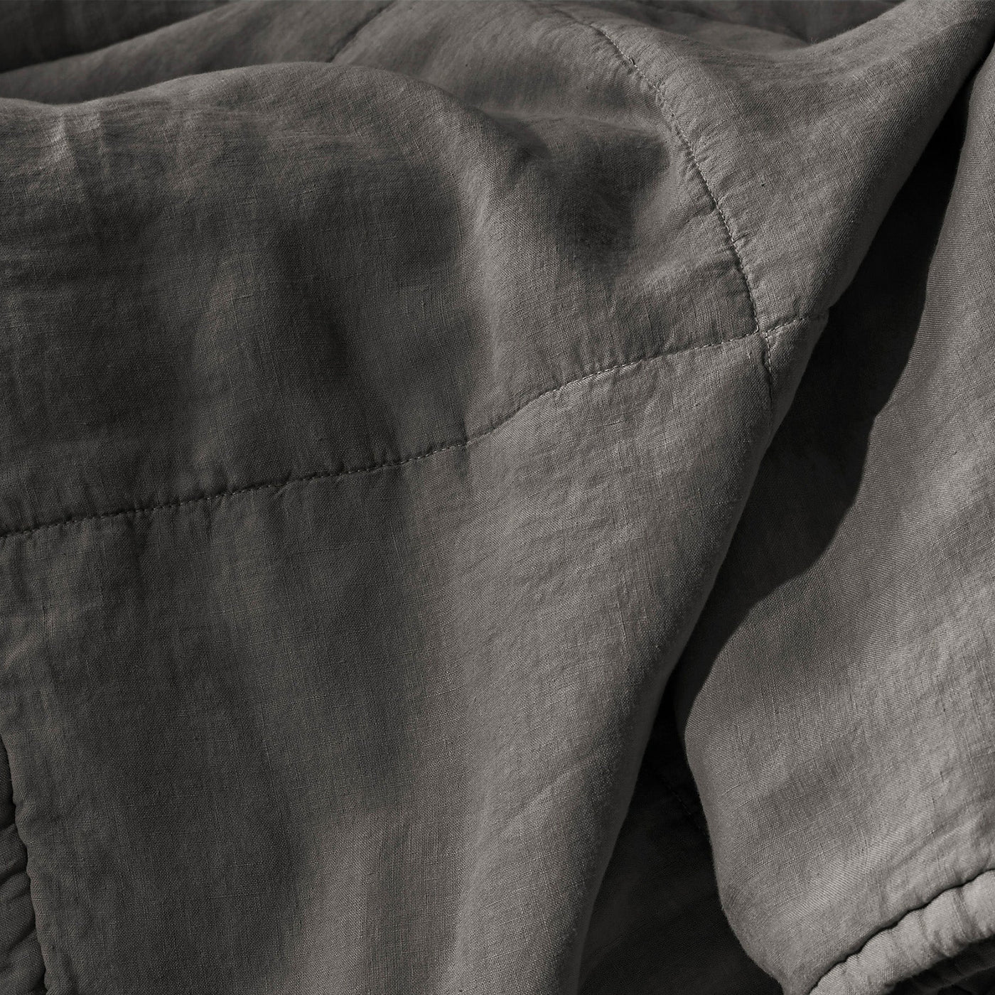 Close-up of Society Limonta Rem quilt in charcoal, showing diamond stitching on washed linen.