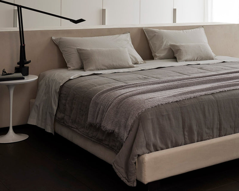 Modern bedroom with a bed, side table, and lamp.