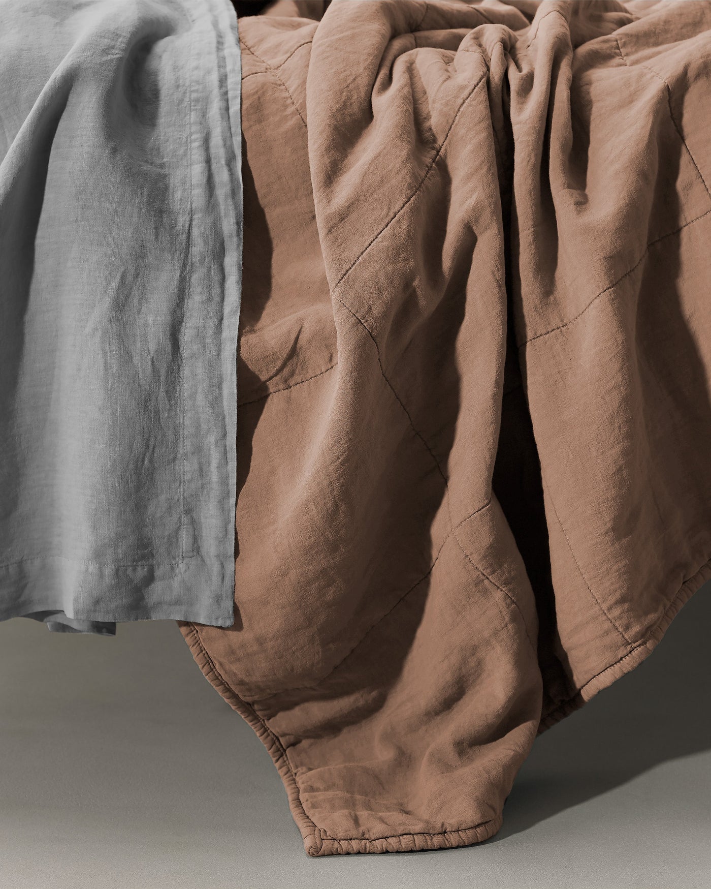 Close-up of Society Limonta Rem quilt in terracotta linen with diamond quilting detail.