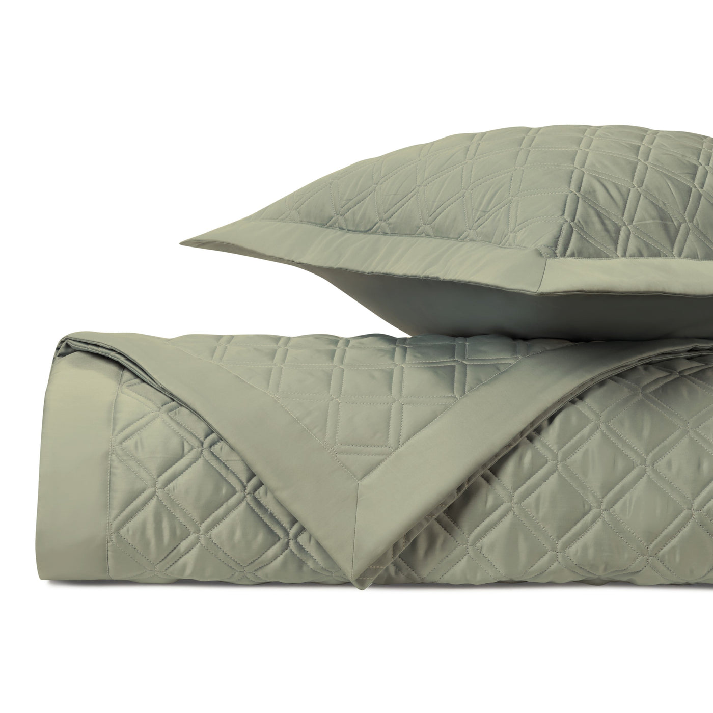 Close-up of sage quilted diamond-pattern coverlet and sham, folded to show texture.