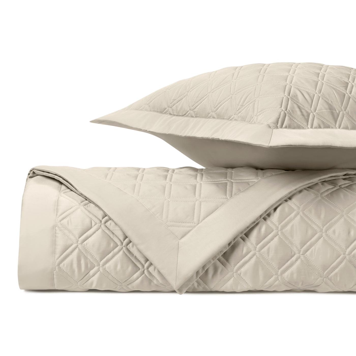 Close-up of ivory quilted diamond-stitched coverlet and sham, neatly folded.