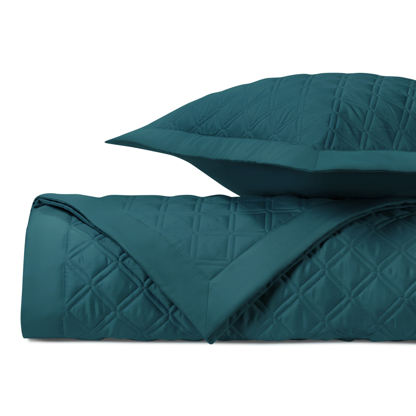 Close-up of teal quilted cotton coverlet and sham showing diamond stitching pattern.