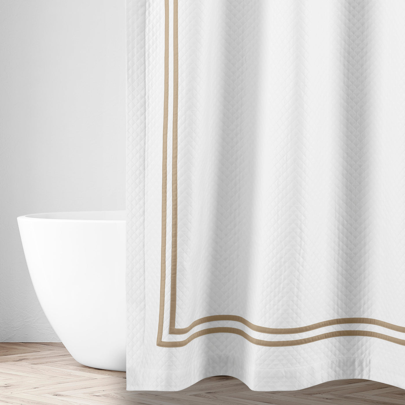 White matelassé shower curtain with double champagne satin border trim, styled in a bathroom.