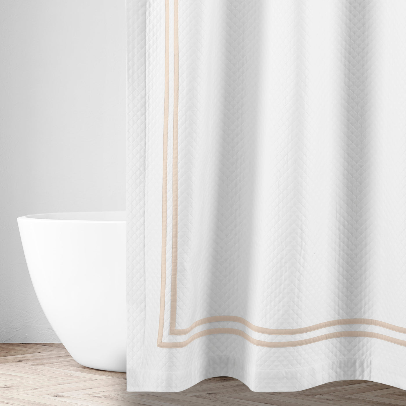 White matelassé shower curtain with champagne double-stripe border, styled in a bathroom setting.