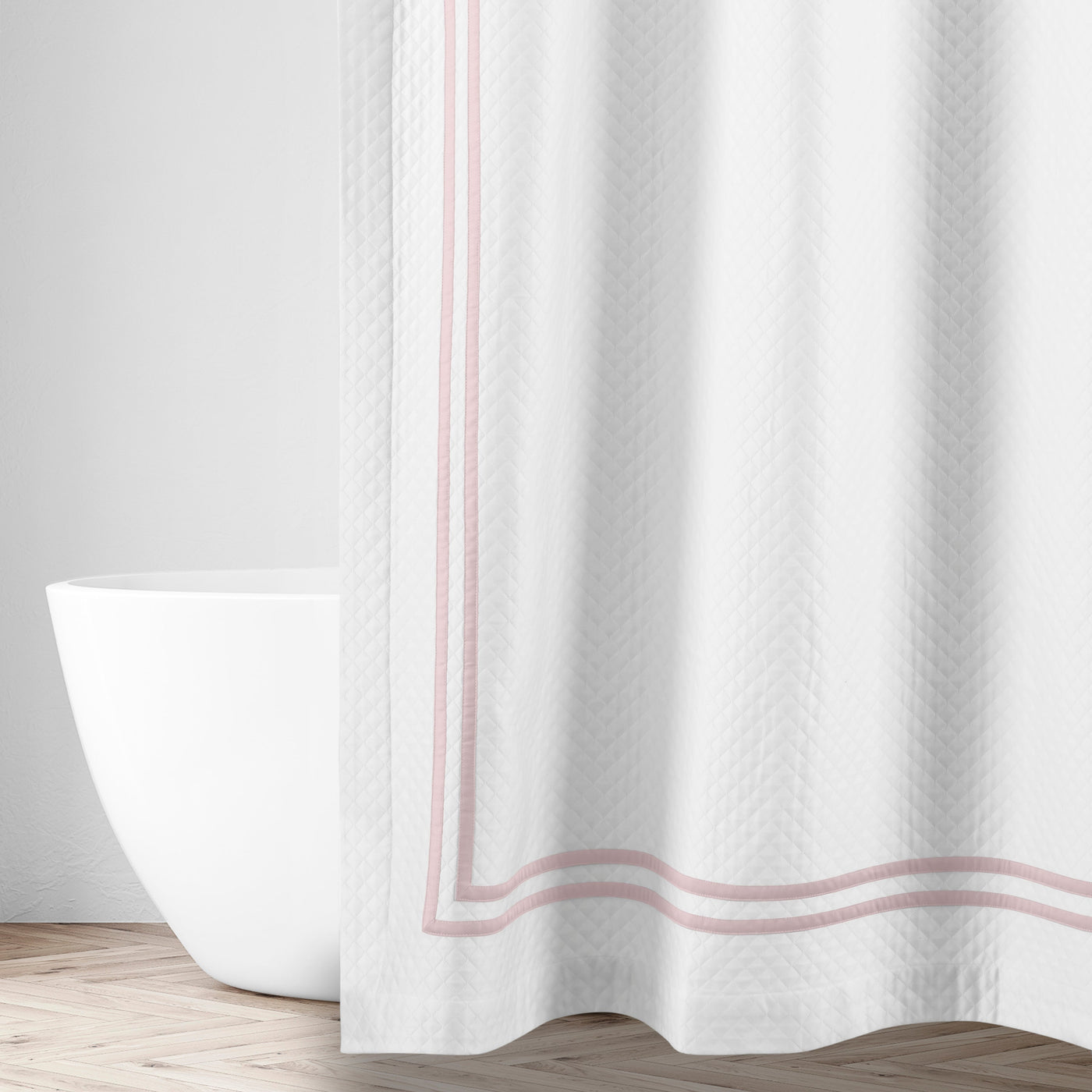 White matelassé shower curtain with blush double-stripe border, styled in a bright bathroom.
