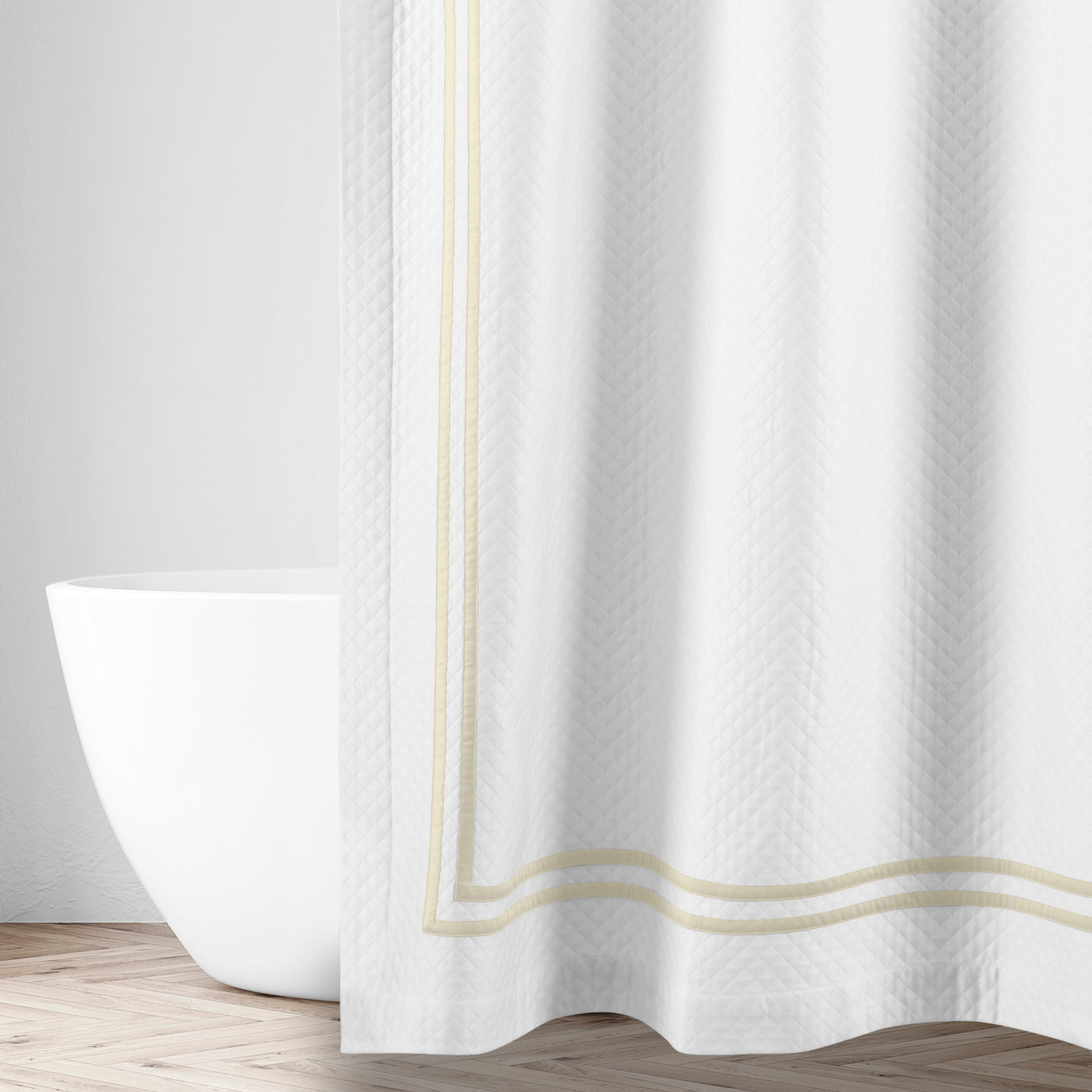White matelassé shower curtain with champagne double-stripe border trim, styled in a bathroom.
