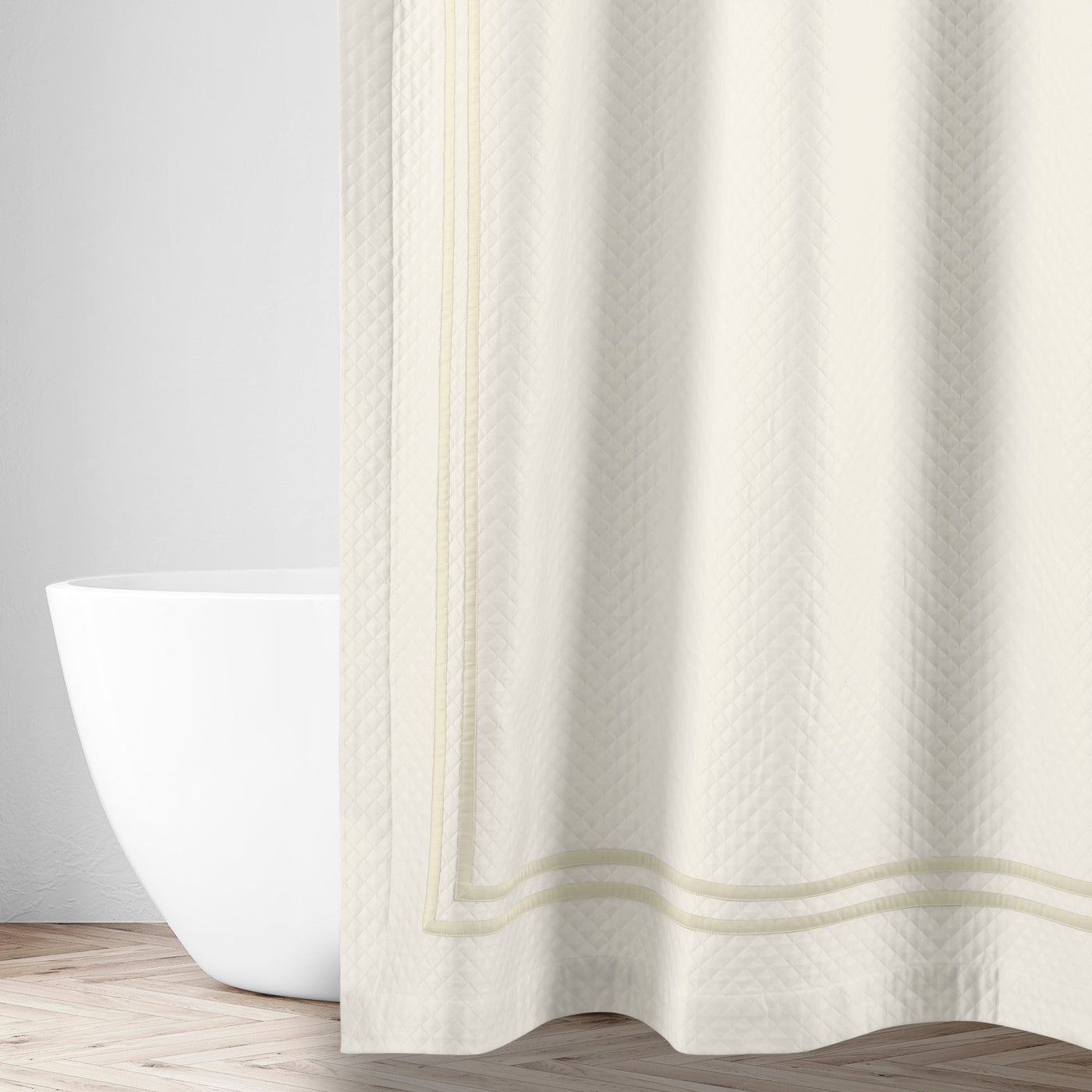 Ivory matelassé shower curtain with tonal herringbone weave and double-stripe hem detail.