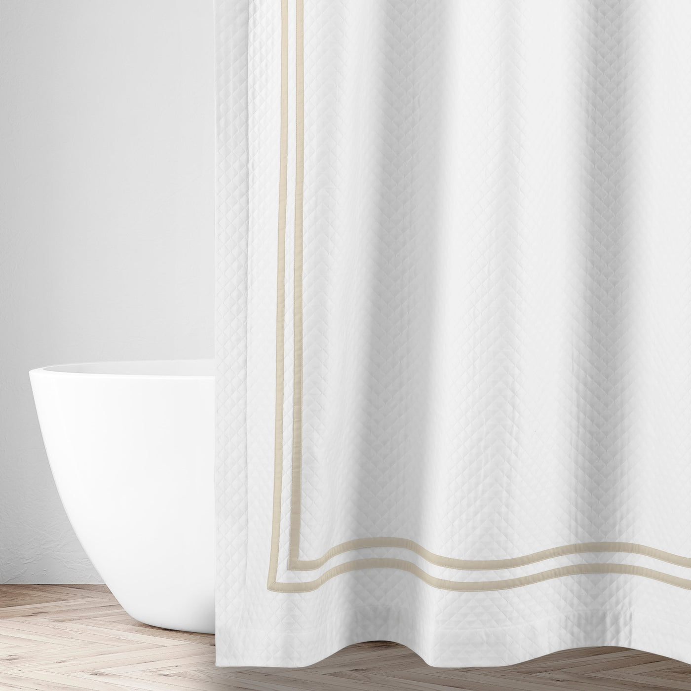 White matelassé shower curtain with champagne double-stripe border trim, styled in a bathroom.