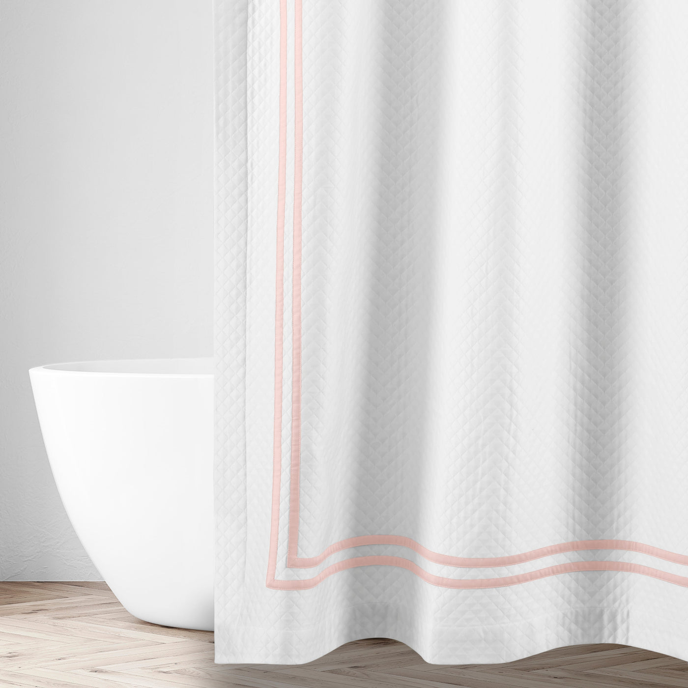 Blush double-stripe border detail on white textured shower curtain, bathtub in background.