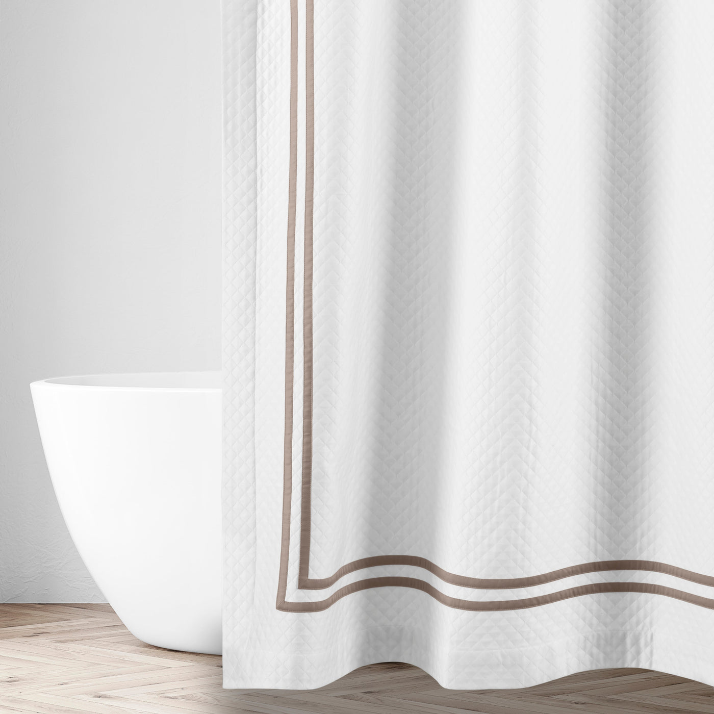 White matelassé shower curtain with double taupe ribbon border trim, styled in bathroom.