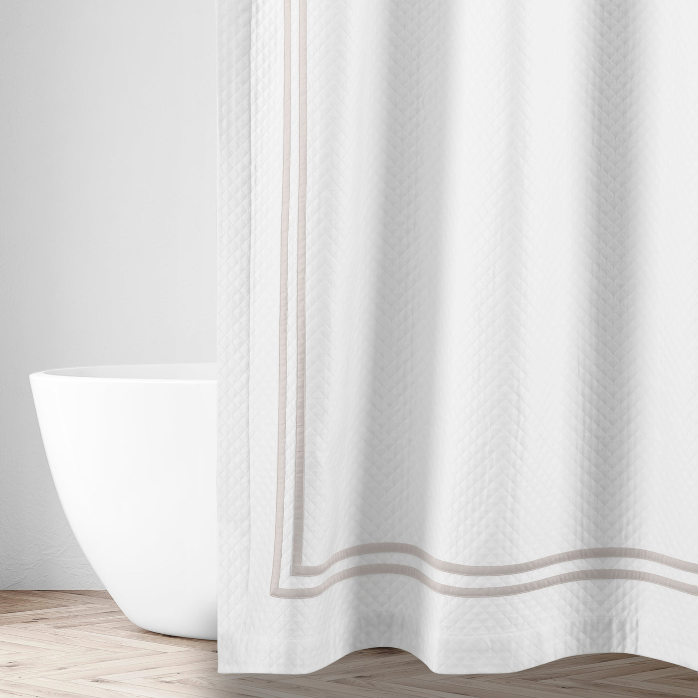 White matelassé shower curtain with taupe double-stripe border, styled in a bright bathroom.