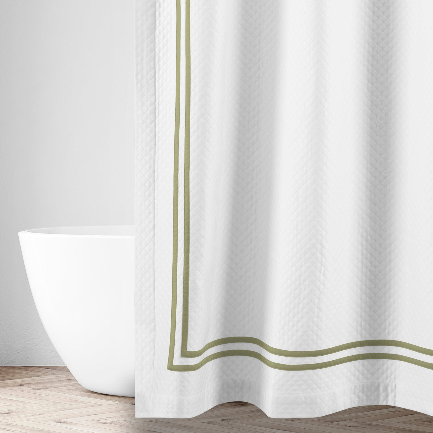 Close-up of white matelassé fabric with double sage green border trim detail.