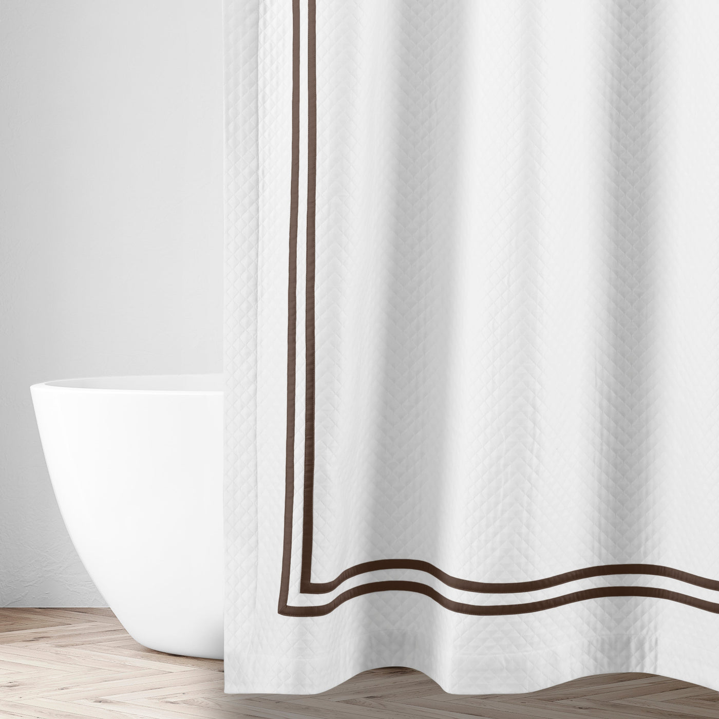 Close-up of white matelassé fabric with double espresso embroidered border trim.