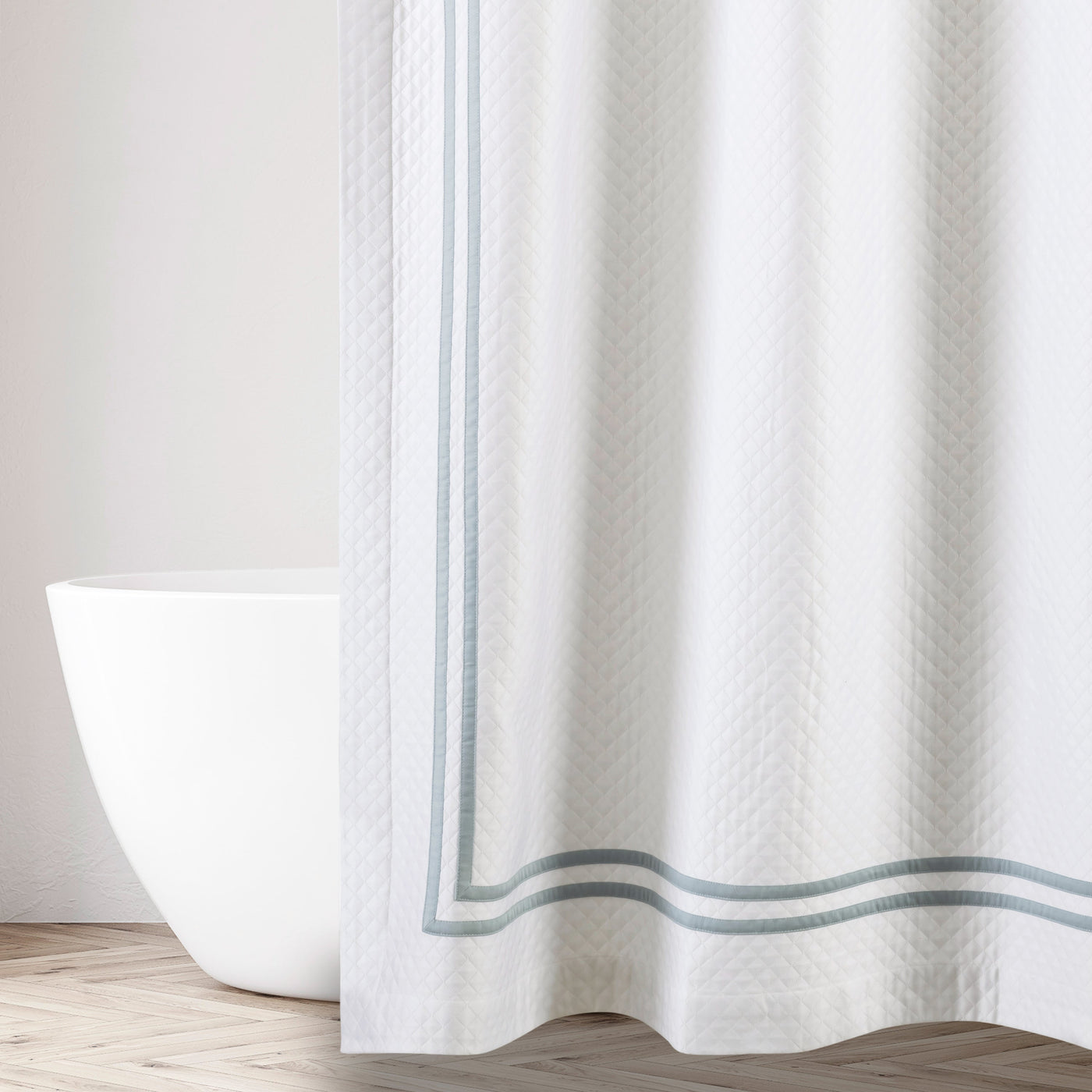 Ivory matelassé shower curtain with sage double-border trim, styled beside a freestanding tub.