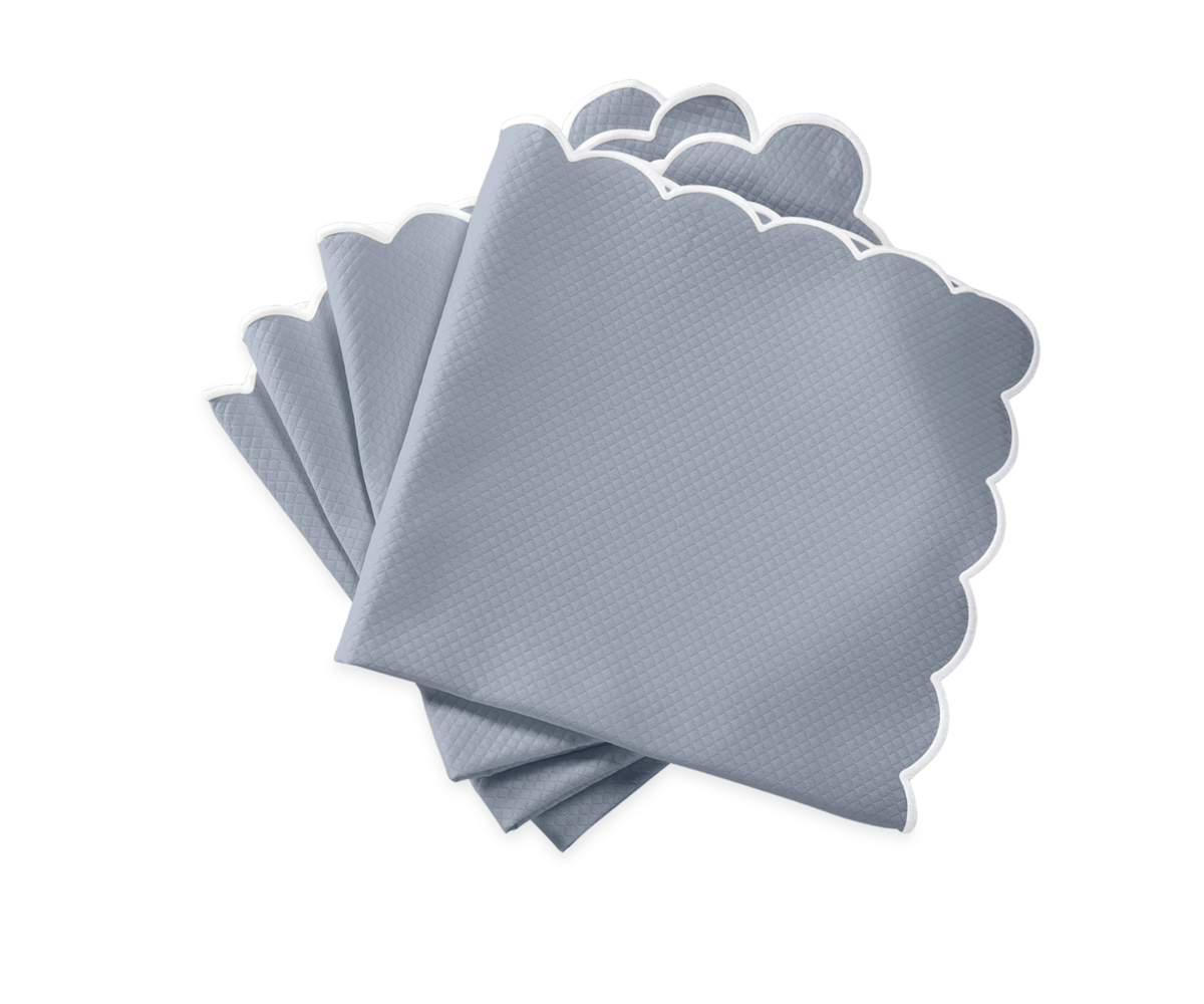 Five Savannah Gardens napkins by Matouk, in light gray with scalloped white edges, are fanned out on a white background, showcasing the timeless elegance of these table linens.