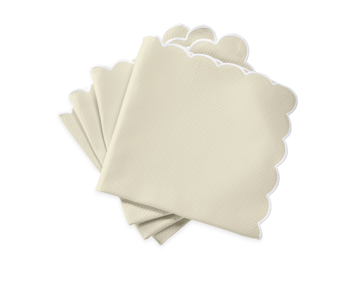 The Savannah Gardens Napkin Set by Matouk features five beige napkins with scalloped white edges, arranged on a white background to perfectly complement diamond pique table linens for a classic, easy-care table setting.