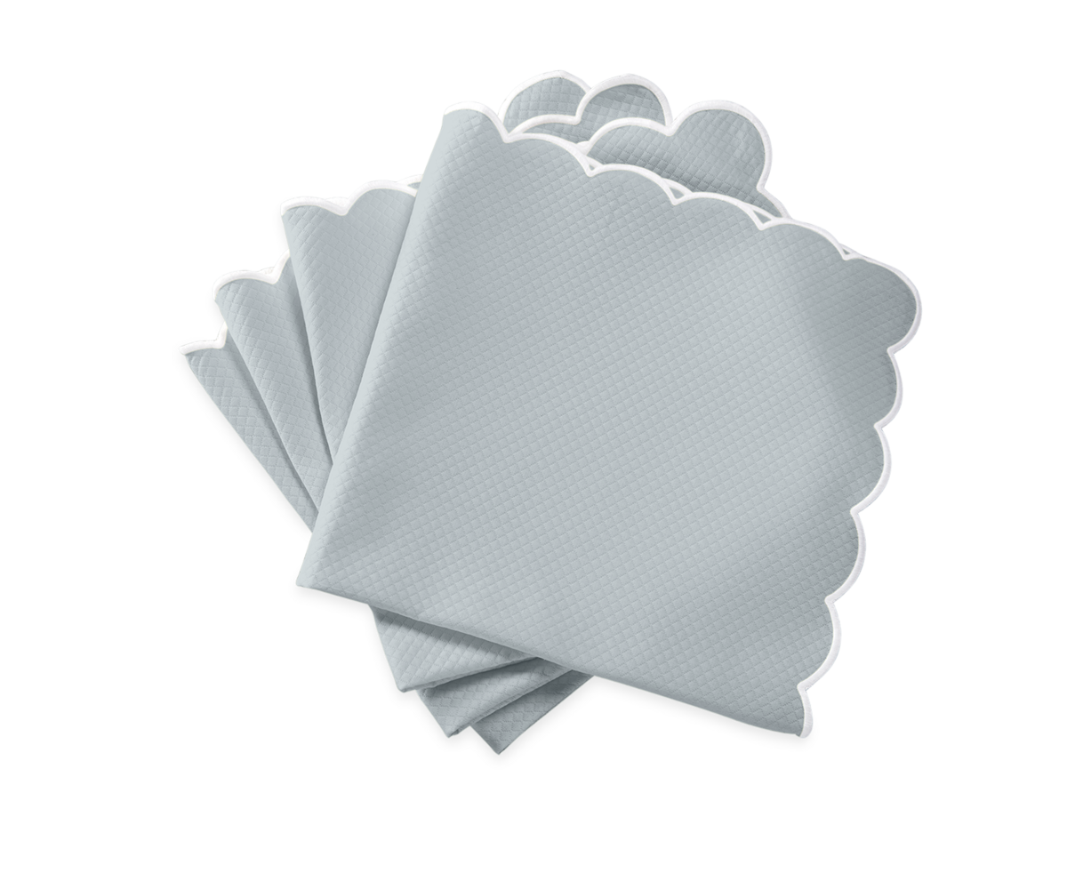 A set of four light gray Matouk Savannah Gardens napkins with scalloped edges, stacked slightly offset on a plain white background.