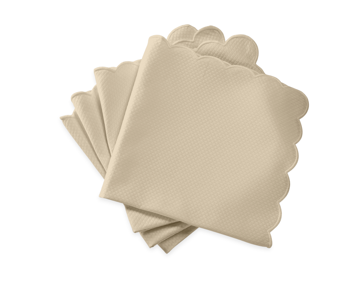 The Savannah Gardens Napkin Set by Matouk features four beige fabric napkins with scalloped edges, perfect for an elegant table setting and pairing beautifully with diamond pique table linens.