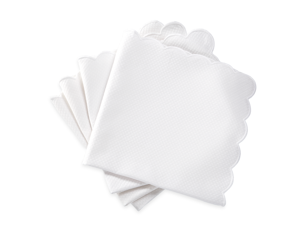 Five white Savannah Gardens napkins by Matouk, featuring scalloped edges, are neatly stacked on a white background, highlighting the timeless elegance of these refined table linens.