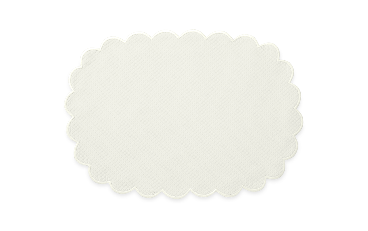 The Savannah Gardens Placemat Set by Matouk features oval, off-white placemats with scalloped edges and a subtle diamond pique design, shown on a light grey background.