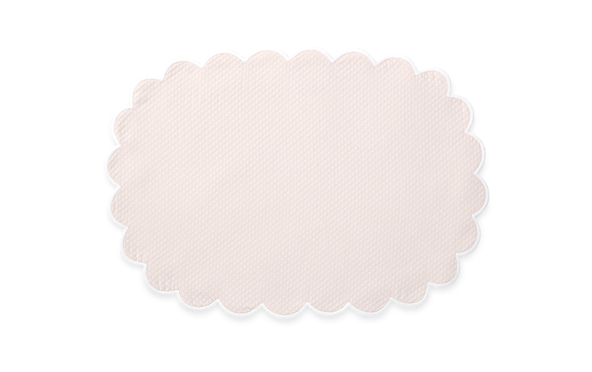 The Matouk Savannah Gardens | Placemat Set features oval-shaped, light beige placemats with scalloped edges, crafted from elegant diamond pique, shown on a plain white background.