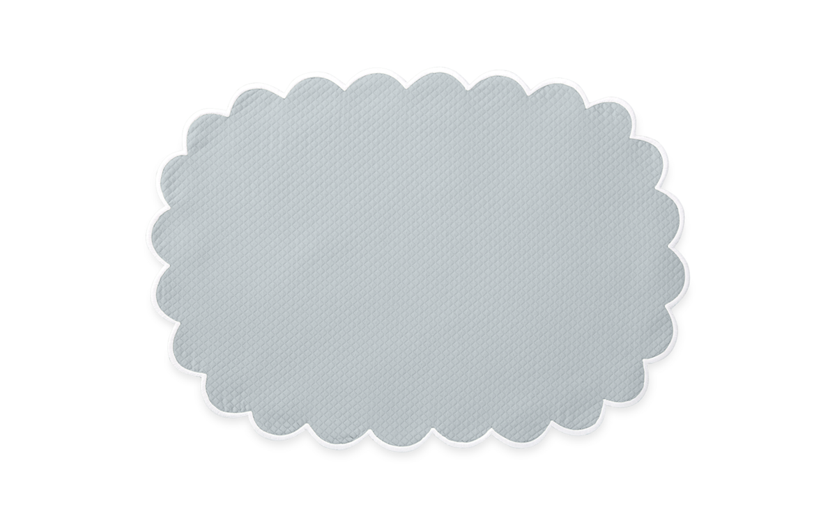 The Matouk Savannah Gardens placemat set features light gray, oval-shaped mats with scalloped edges and a subtle diamond pique pattern, inspired by elegant Matouk table linens and shown on a plain white background.
