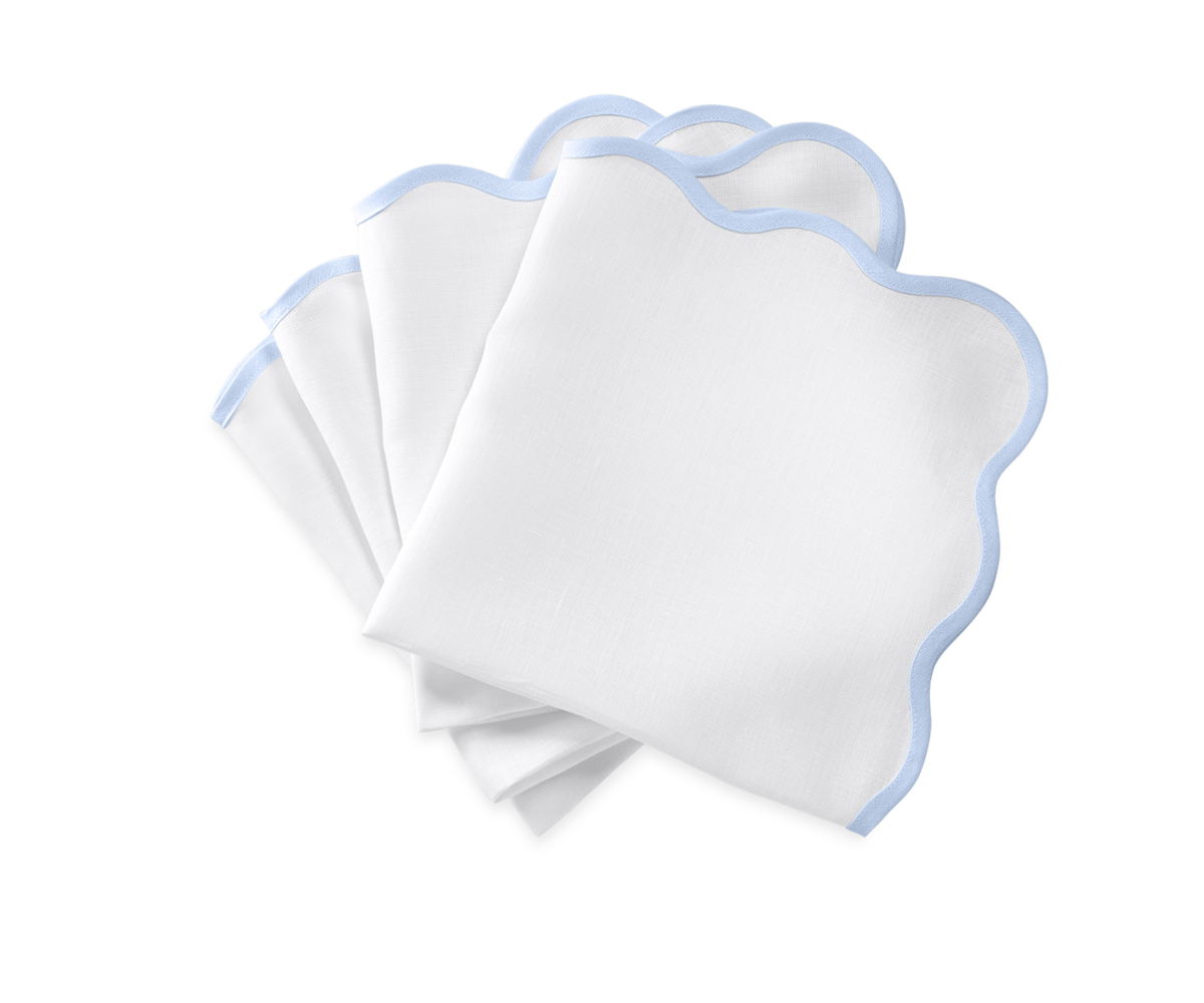 The Matouk Scallop Edge | Napkin Set features four white napkins with light blue trim, elegantly arranged on a white background—ideal for unique tablescapes or pairing with your favorite linen placemats.