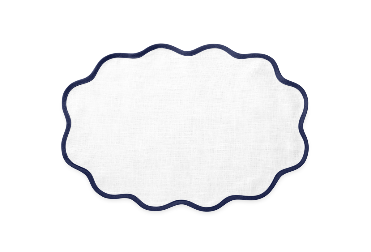 The Scallop Edge Placemat Set by Matouk features a white oval design with a wavy dark blue border—ideal for a unique tablescape. It pairs beautifully with Scallop Edge Napkins and other linen placemats for a stylish setting.