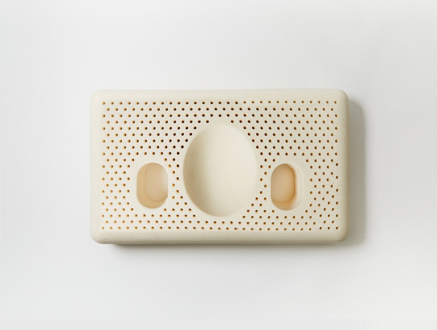 Coyuchi Turiya Latex pillow underside showing ventilation holes and ergonomic cutouts, ivory.