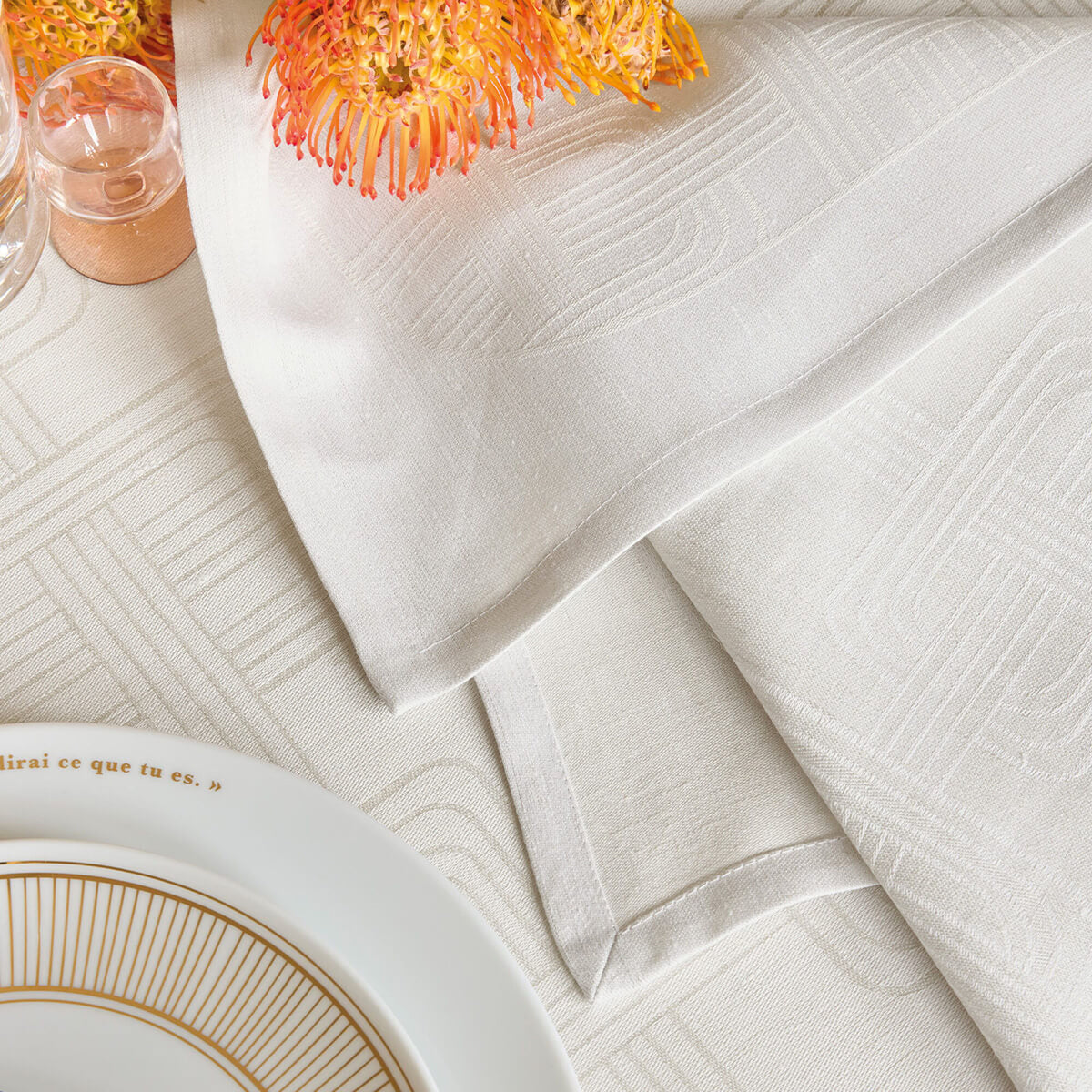Le Jacquard Français Hôtel Particulier Gray napkin folded on table, geometric jacquard weave detail.