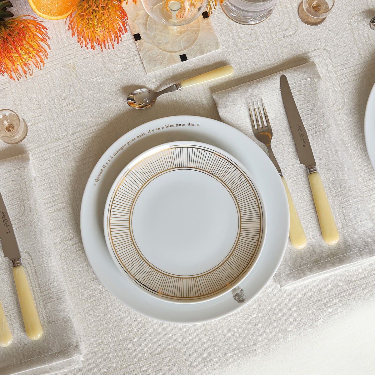 Le Jacquard Français Hôtel Particulier gray napkin styled in place setting with gold-rimmed plates.