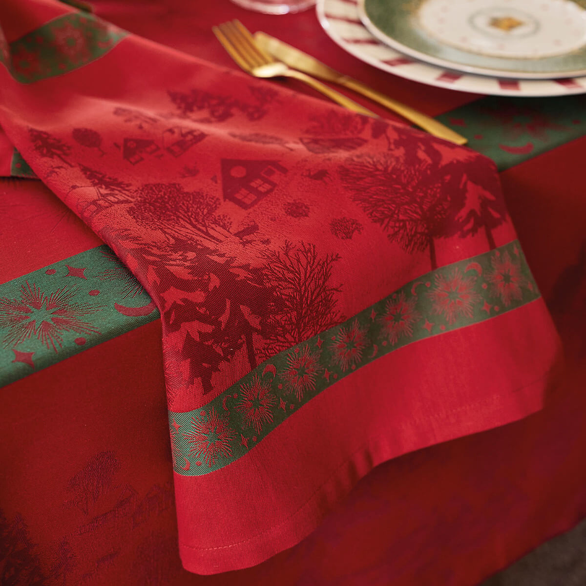 Close-up of Le Jacquard Français Sous les Étoiles red jacquard with woven winter scene and green snowflake border.