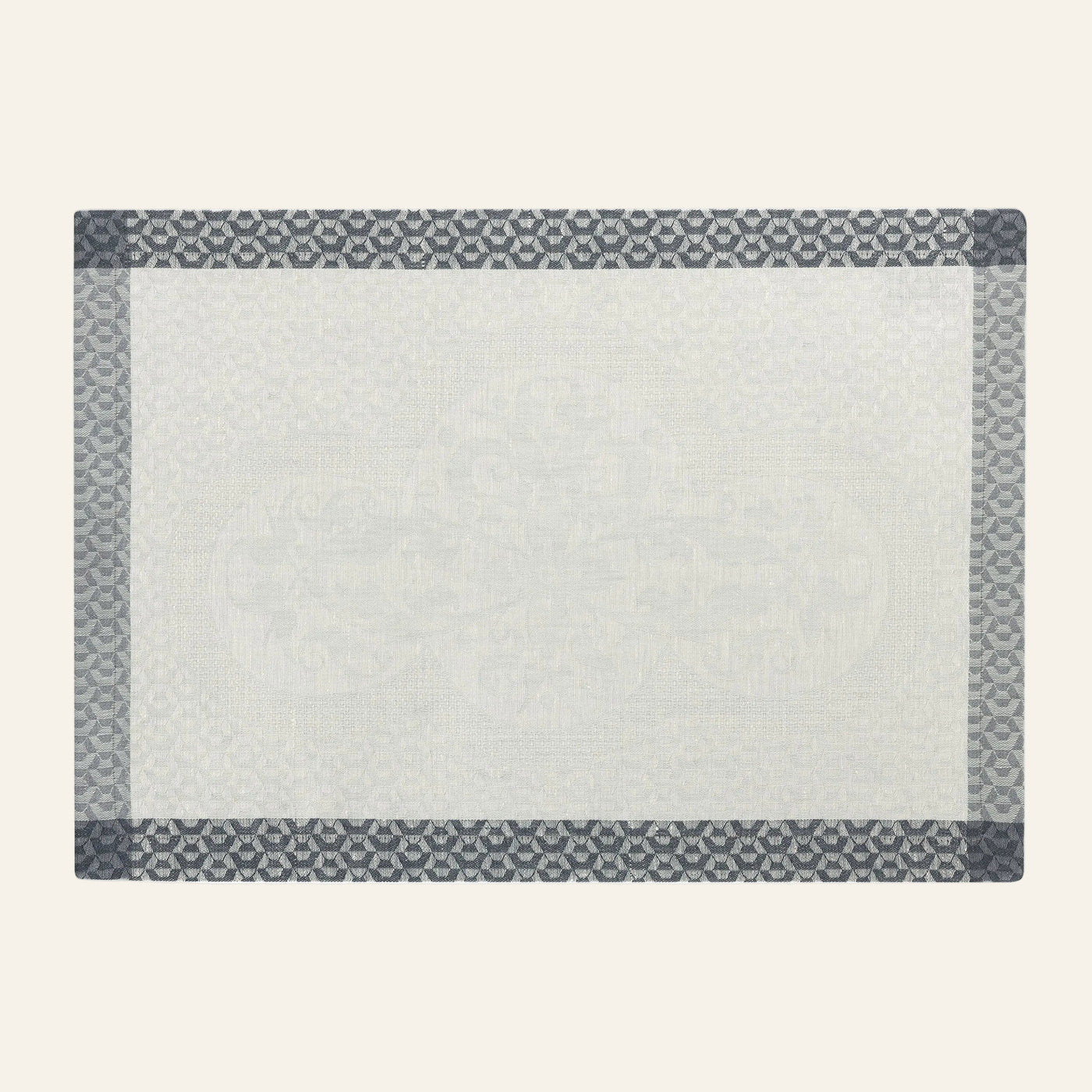 Le Jacquard Français Évasion Céleste ivory placemat with slate geometric border pattern.