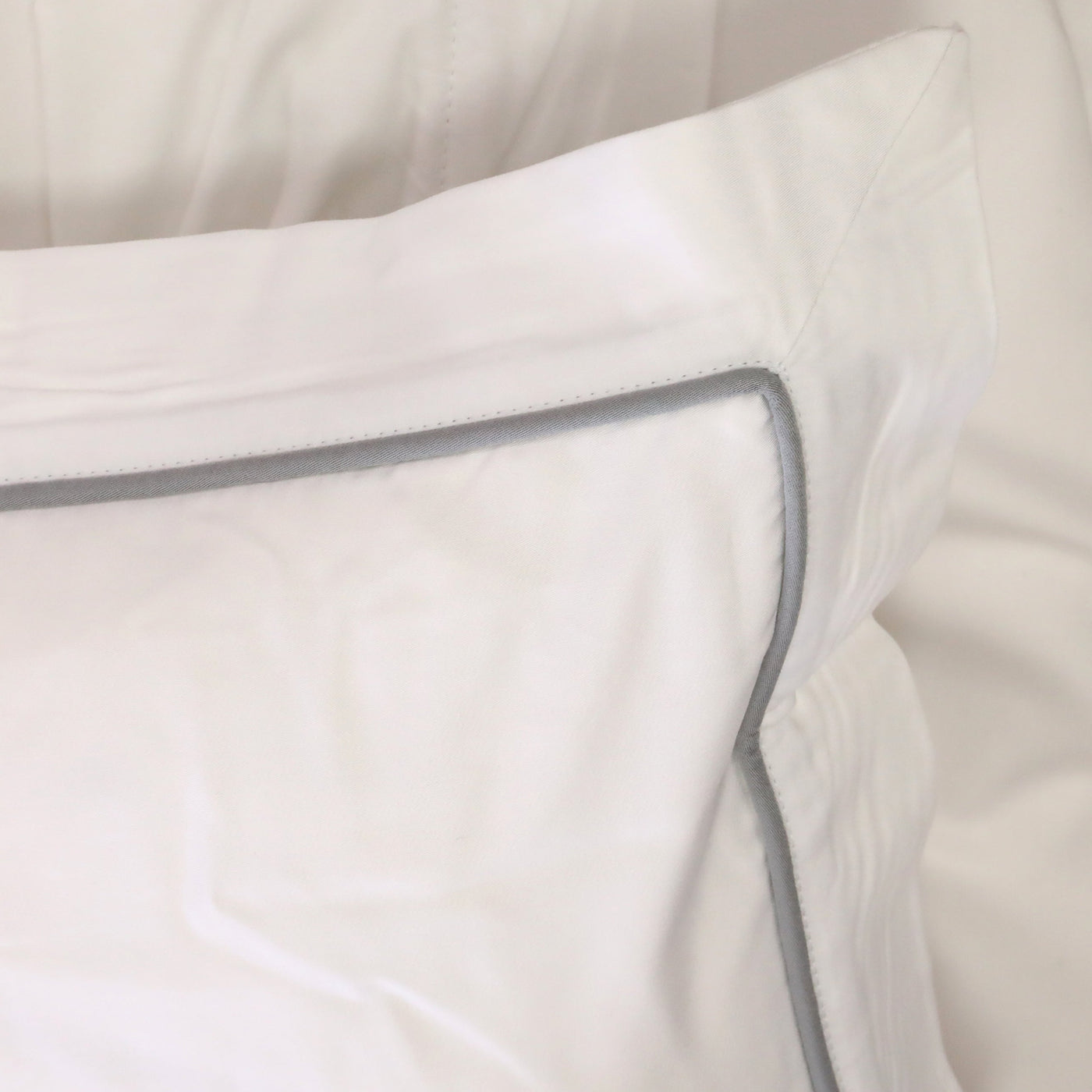 Close-up of a white pillow with a gray border on a light background