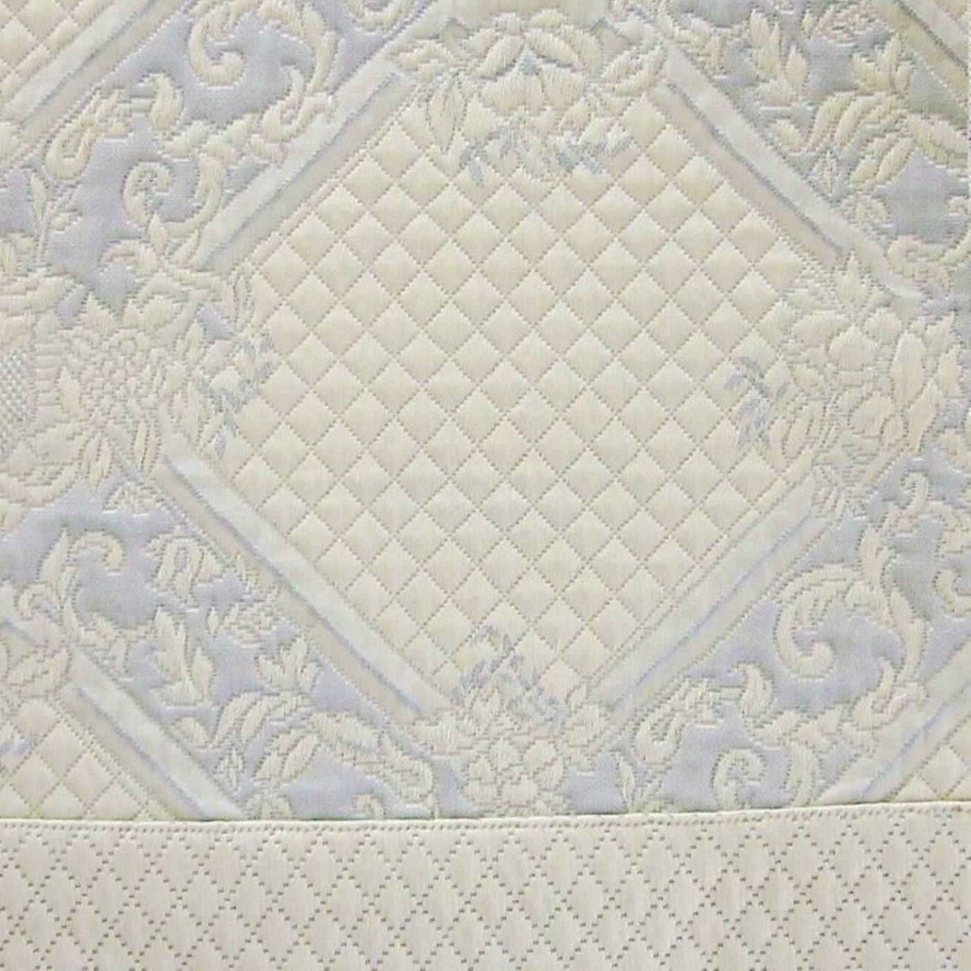 Close-up of ivory quilted diamond pattern with floral jacquard border detail.
