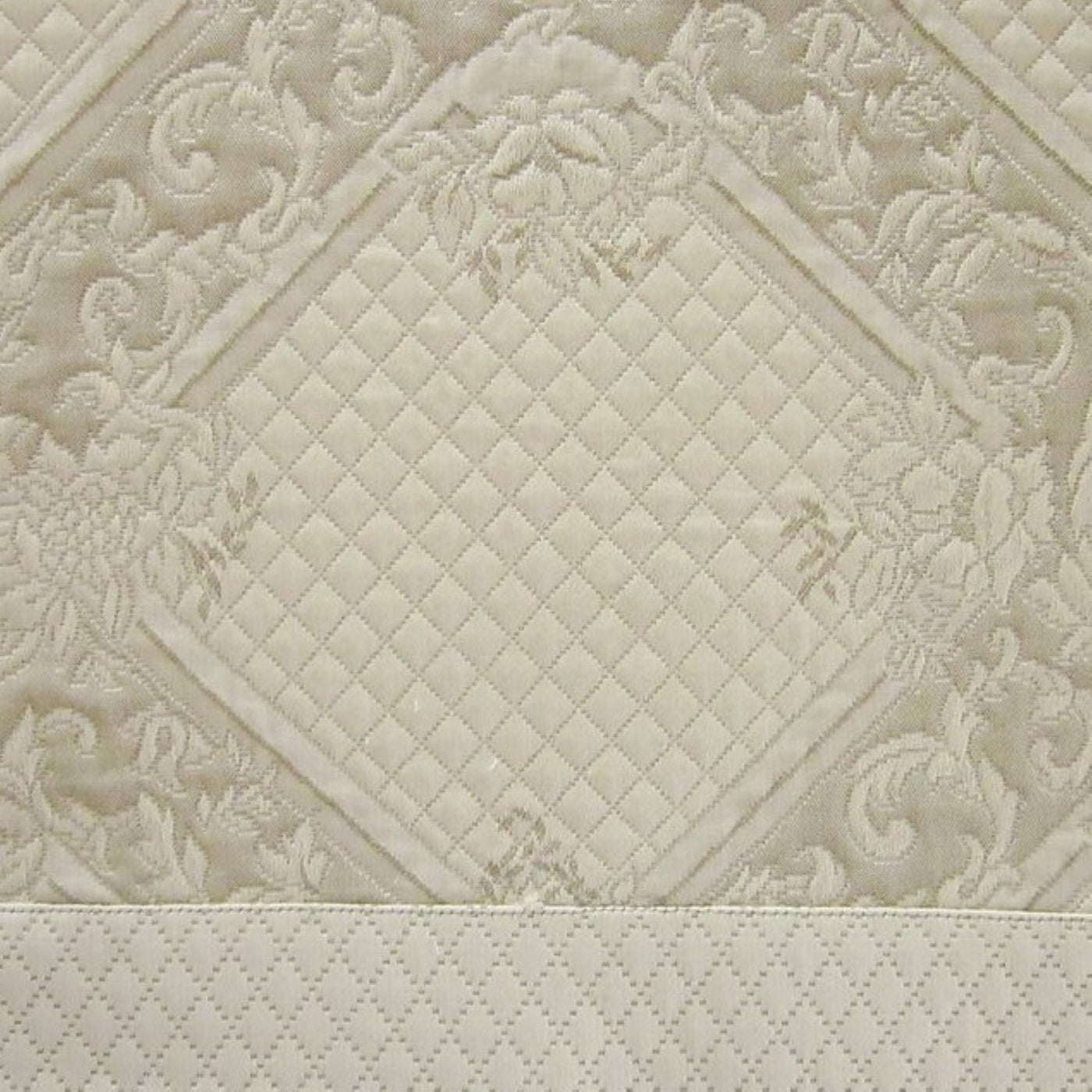 Close-up of ivory Shiraz quilted cotton fabric with diamond stitching and floral damask pattern.