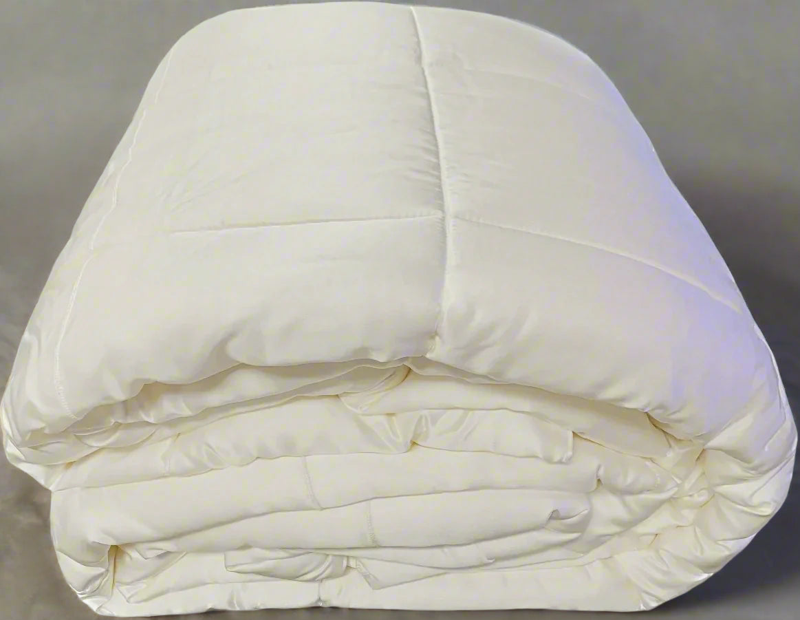 A neatly folded Kumi Kookoon Silk Covered Silk-filled Comforter, prized for its hypoallergenic qualities, rests on a neutral surface.