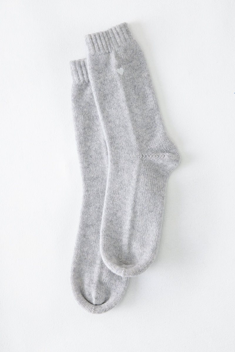 A pair of The Matouk Sleeping Socks by Matouk in light gray, made in Scotland, are laid flat on a white surface.