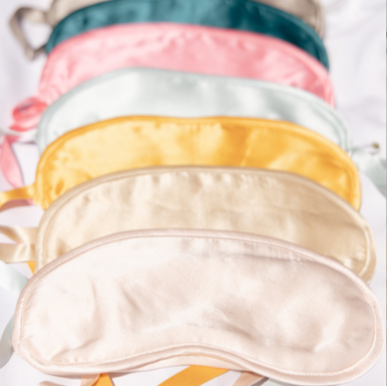Silk-filled Sleep Masks by Kumi Kookoon in pastel colors are arranged on a white surface, each crafted from luxurious silk charmeuse.