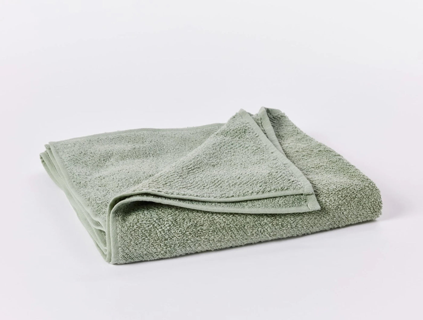 Folded sage green terry guest towel with visible looped texture and corner detail.