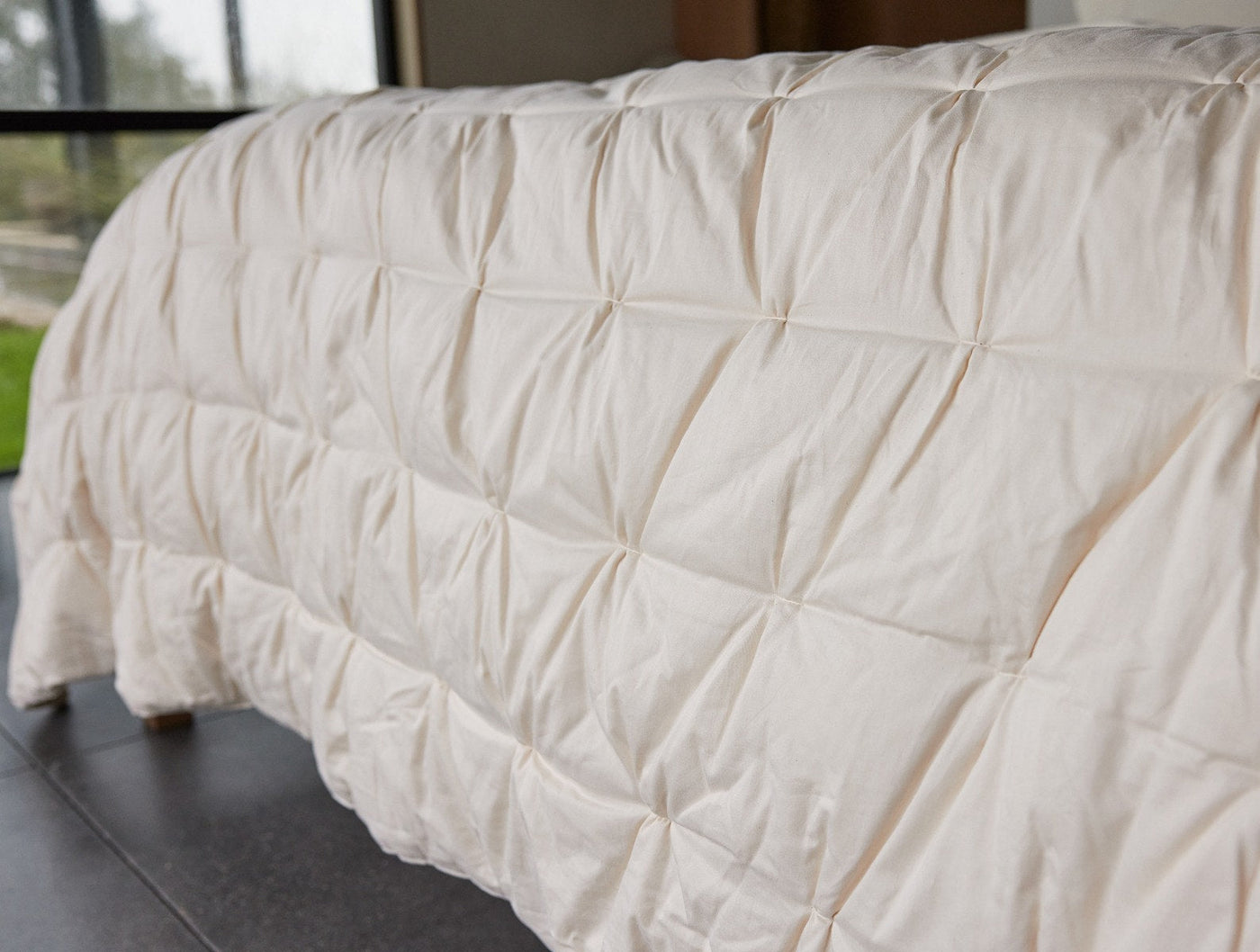 Close-up of Coyuchi duvet insert showing ivory pintuck quilting texture and soft cotton fill.