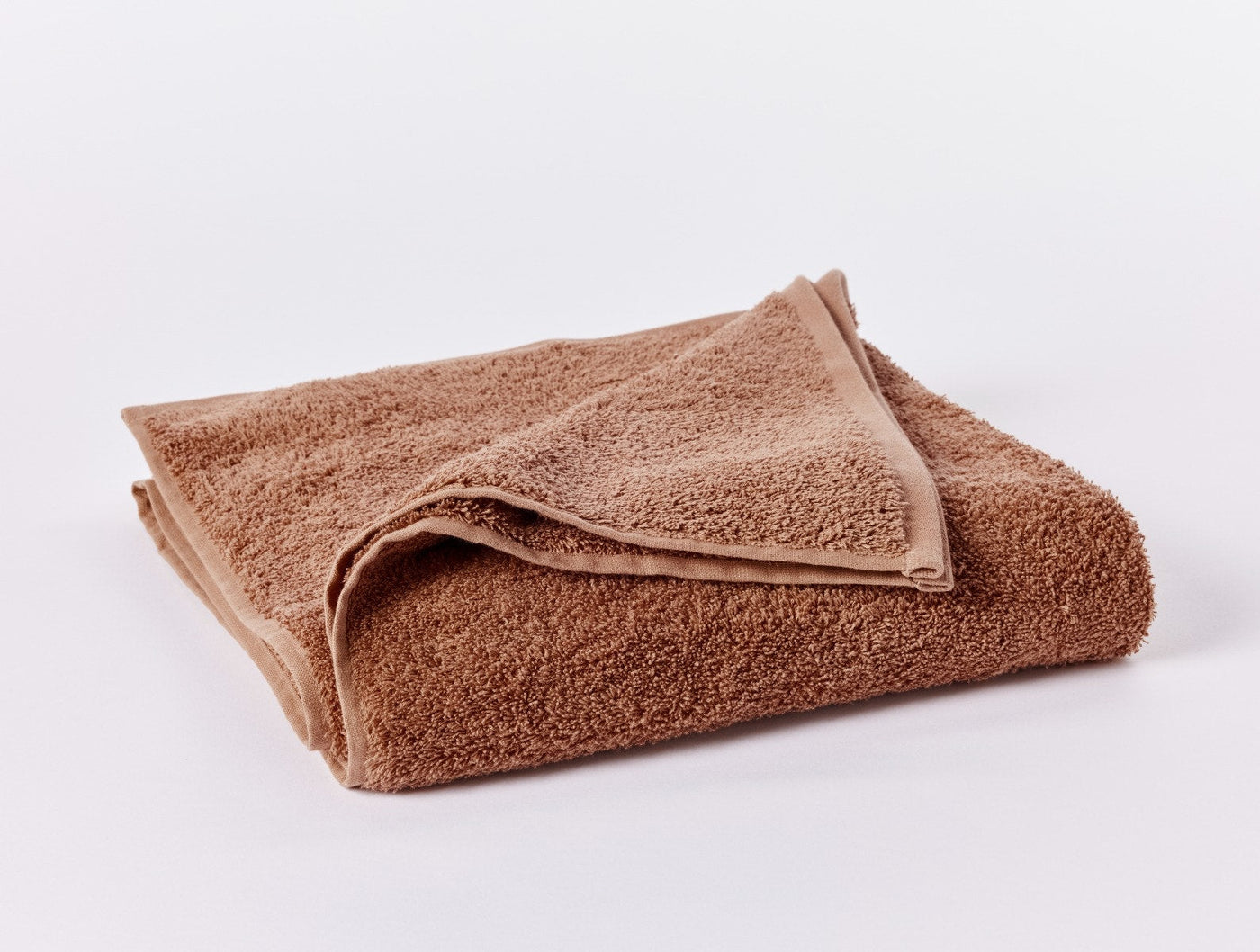 Coyuchi Cloud Loom wash cloth folded, showing caramel terry texture and corner detail.