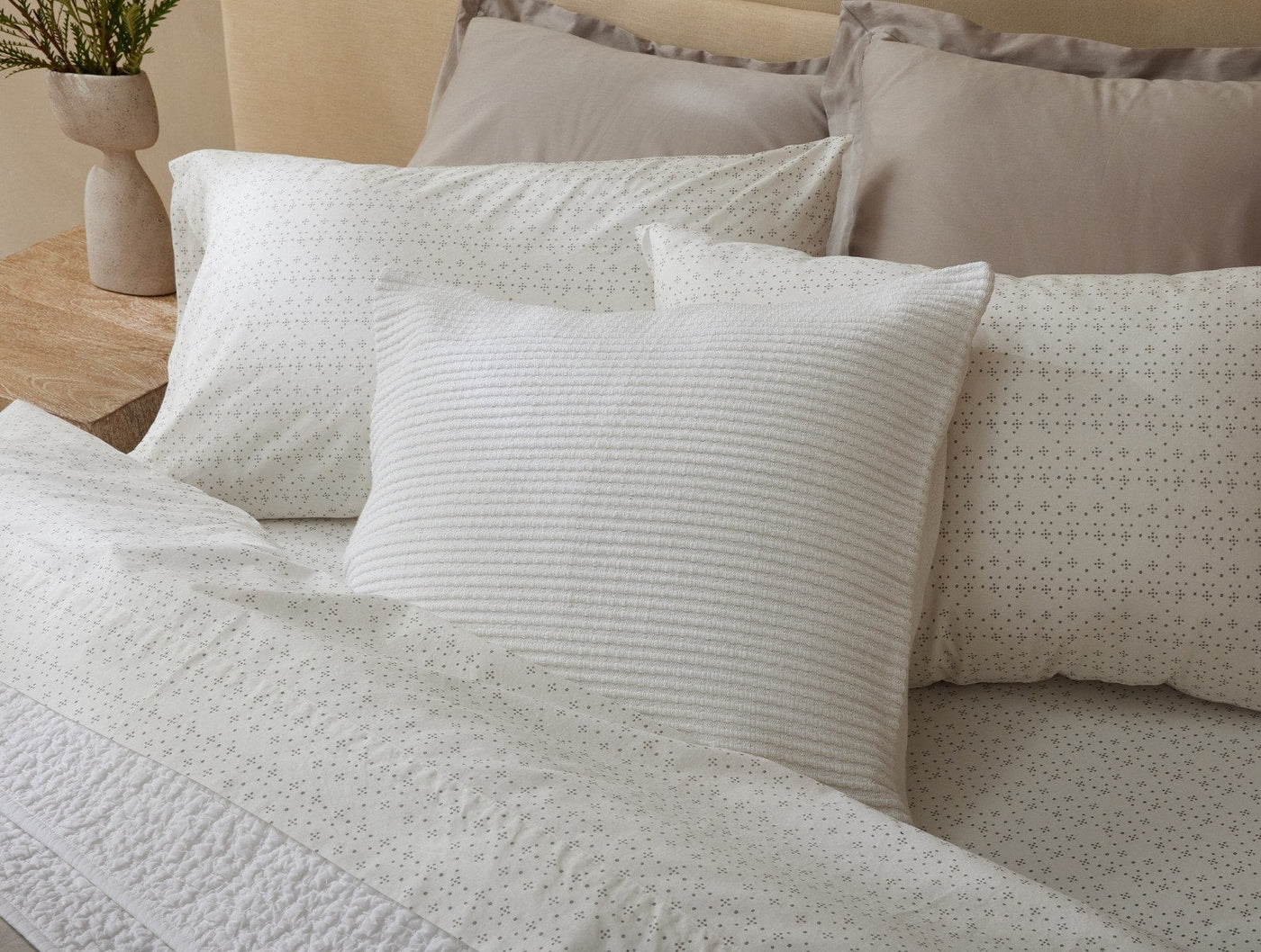 Coyuchi Marshall ivory striped lumbar pillow styled on a bed with patterned white bedding.